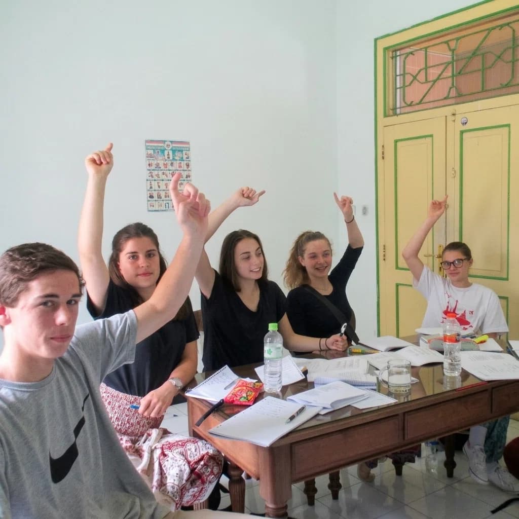 Puri Bahasa students raising their hands enthusiastically in a classroom