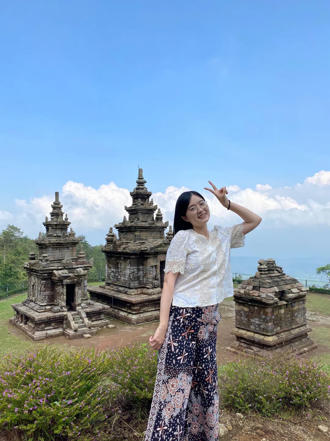 A Puri Bahasa student posing at an ancient Hindu temple complex