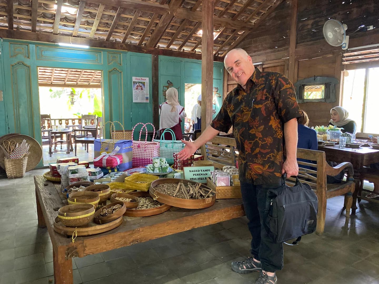 A Puri Bahasa student in batik attire at a traditional Indonesian market stall