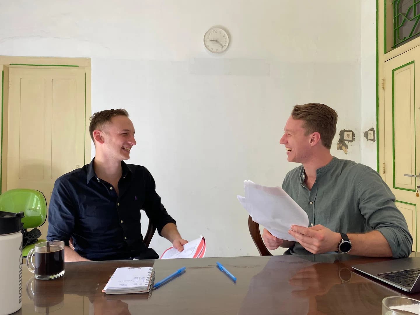 Puri Bahasa students laughing while exchanging papers during a lesson