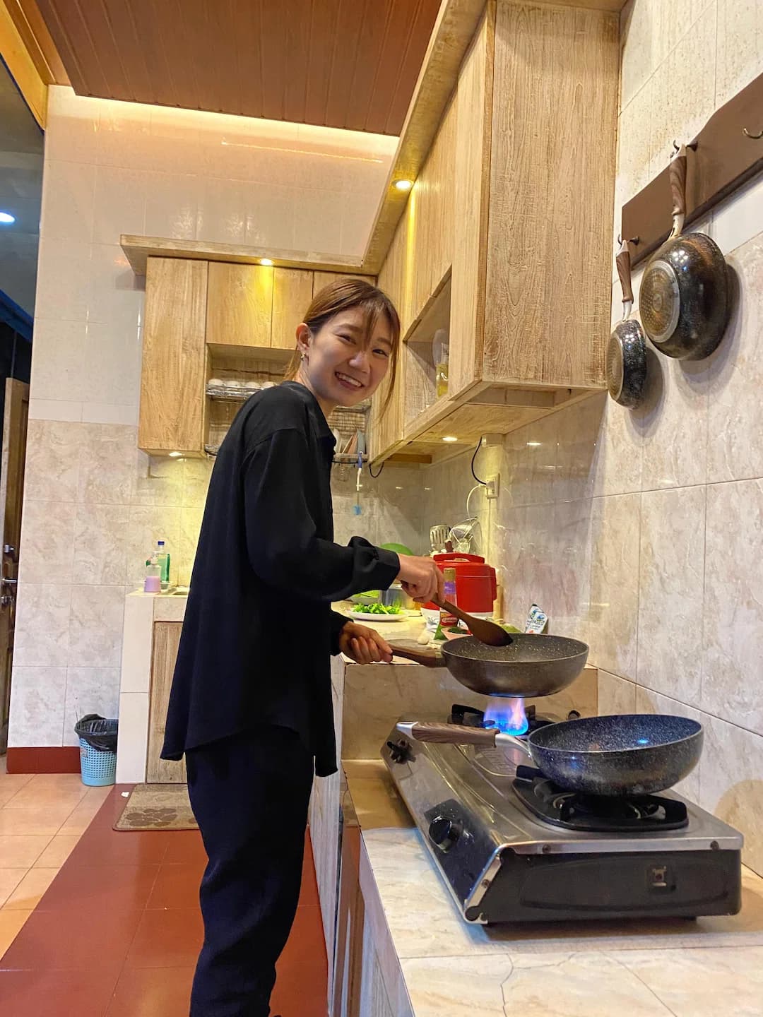 A Puri Bahasa student cooking with a wok on a gas stove