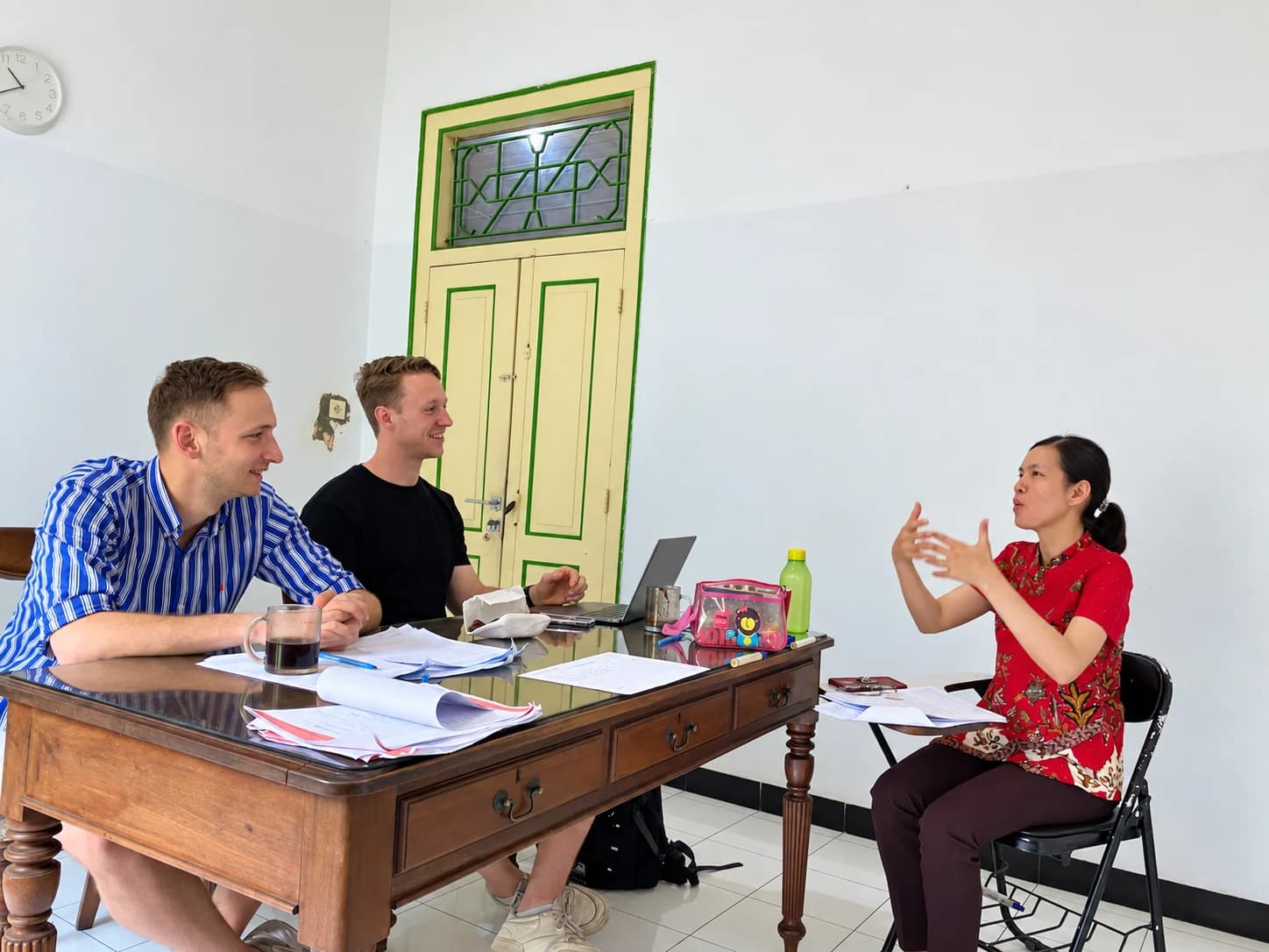 A teacher explaining Indonesian to two students during a lesson at Puri Bahasa